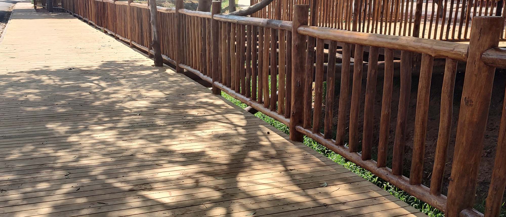 Deck de réguas de pinus tratado com guarda-corpo de toras de eucalipto e sombra de árvores sobre o piso