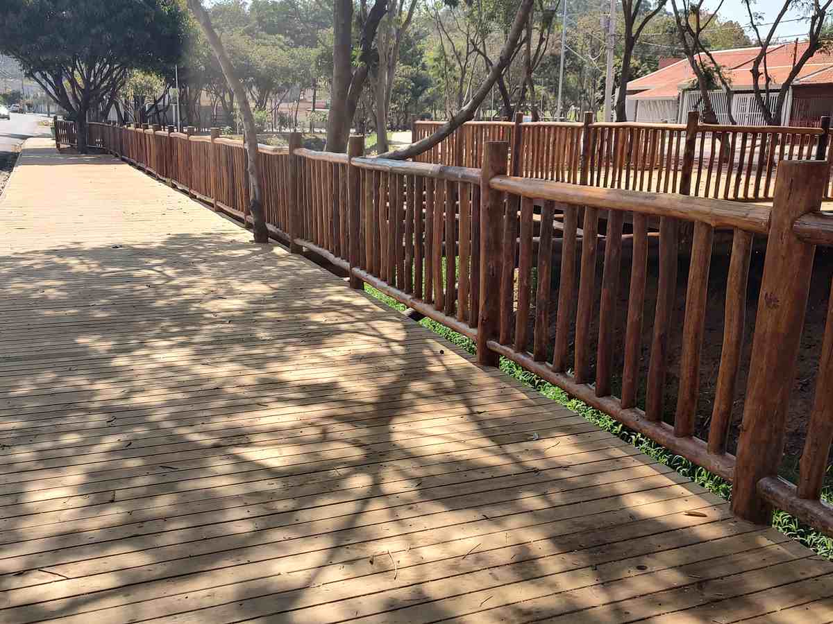 Deck de réguas de pinus tratado com guarda-corpo de toras de eucalipto e sombra de árvores sobre o piso
