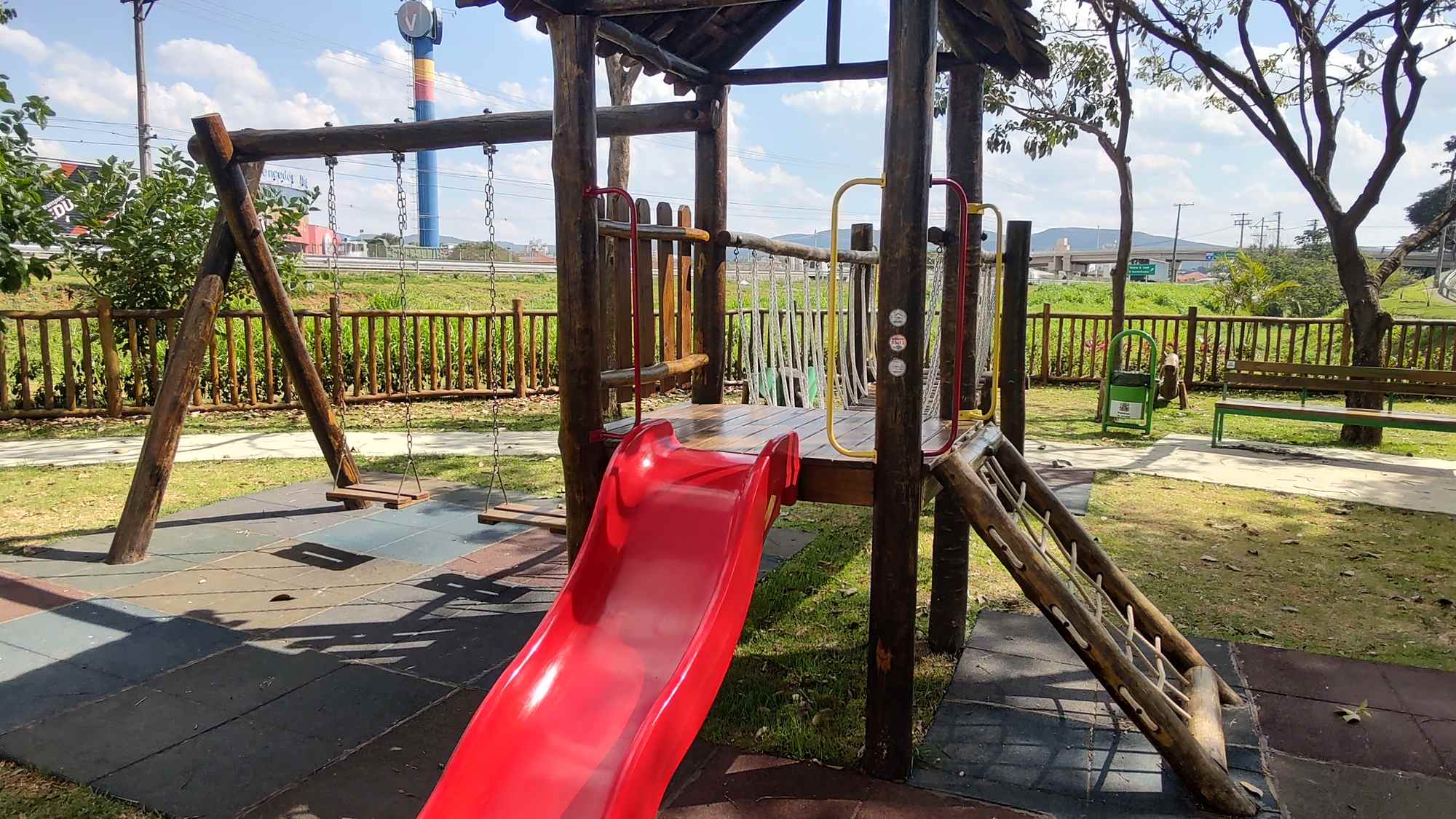 Playground em toras de eucalipto com torre e escorregador vermelho